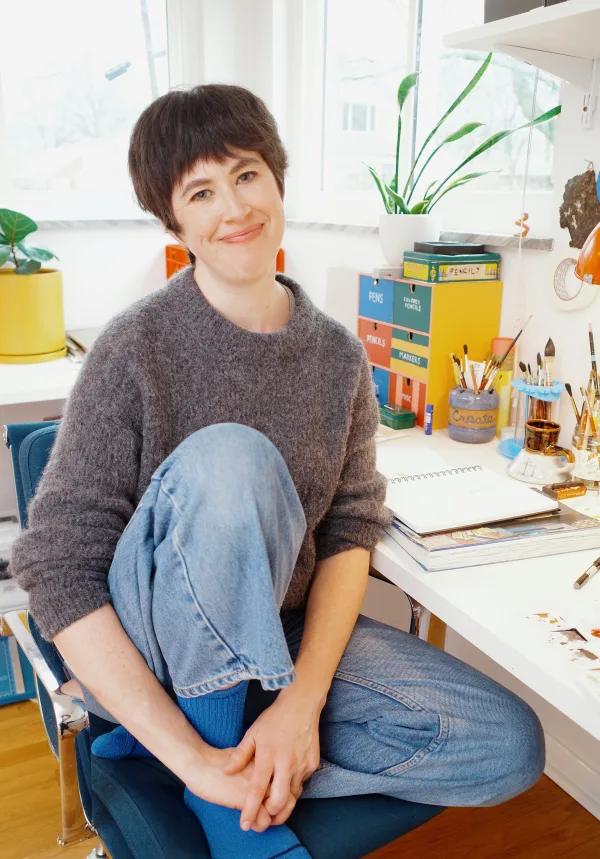 Hallie Bateman at her desk, surrounded by pens, brushes and a sketchbook